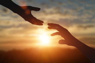 Silhouette of reaching, giving a helping hand, hope and support each other over sunset background....