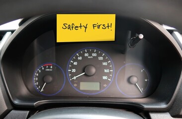 Car console panel with handwritten stick note SAFETY FIRST , concept of car driver self reminder to...