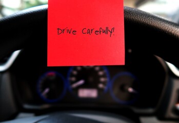 Car console panel with handwritten stick note DRIVE CAREFULLY, concept of car driver self reminder...