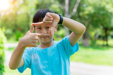 Close up of child girl smiling making frame with hands and fingers. Creativity and photography concept.