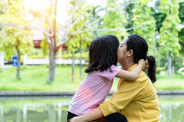 Fototapeta premium Cute young daughter with her mother hugging in love playing together in a park