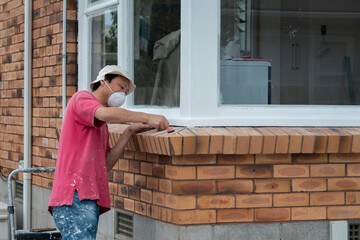 Man painting and cleaning windows of an empty house under renovation. Auckland.