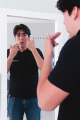 High quality photography. Caucasian man looking in the mirror putting cream on his face to take care of his skin.