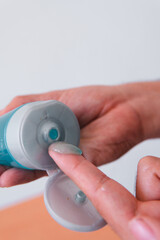 High quality photography. Hand scooping out some blue cream with finger. Man taking some skin cream or toner.