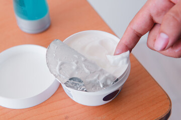 High quality photography. A finger full of skin care cream. Cream being taken from the pot.