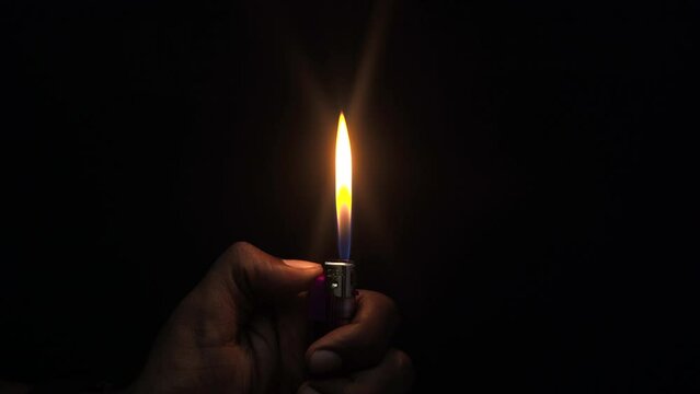 flaming lighter hands in background black closeup view