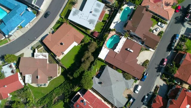 Aerial Top Shot Of Swimming Pools Outside Roofed Houses In City, Drone Flying Backwards On Sunny Day - Los Angeles, California