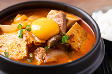 Korean food, Kimchi soup with tofu, pork and fresh egg yolk in Korean stone pot
