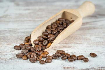 Obraz premium Wooden spoon with coffee beans ready to grind and enjoy their flavor.