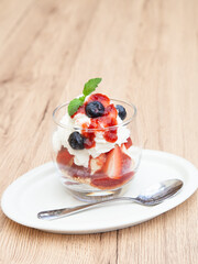 Homemade vanilla ice cream parfait with strawberry, blueberry, whipped cream, cookie crumble and sauce