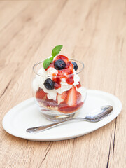 Homemade vanilla ice cream parfait with strawberry, blueberry, whipped cream, cookie crumble and sauce