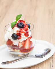 Homemade vanilla ice cream parfait with strawberry, blueberry, whipped cream, cookie crumble and sauce