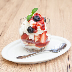 Homemade vanilla ice cream parfait with strawberry, blueberry, whipped cream, cookie crumble and sauce