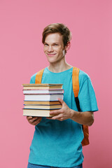 vertical portrait of a handsome, laughing guy with a stack of heavy textbooks in his hands