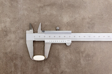 Metal caliper measuring pill size on the rusty grunge background with copy space	