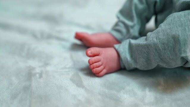 Indoor closeup shot of cute feet and toes of little infant  baby in gray sweatpants. Naps and sleeping habits for children. High quality 4k footage