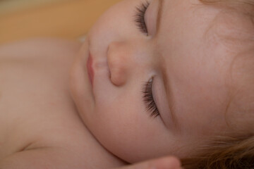 Close up face of baby child sleeping in the bed. Closeup sleepy kids portrait.