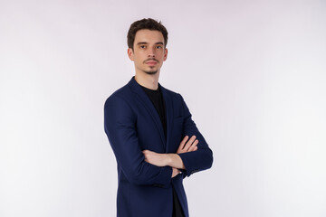 Portrait of young handsome businessman wearing suit standing with crossed arms with isolated on studio white background