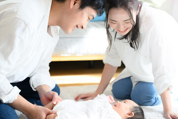 Obraz premium 赤ちゃんをあやすアジア系のお母さんとお父さん