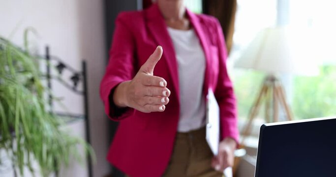 Business woman extends hand towards camera for handshake or greeting