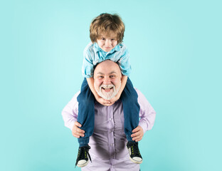 Grandfather and son piggyback ride with funny face isolated on blue in studio. Granddad and cute boy with funny face.