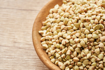 raw buckwheat seed in wood plate on wooden table background. buckwheat grain, buckwheat seeds                                                                                    