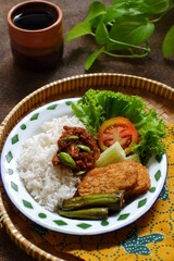 a plate of rice served with sambal and vegetables  