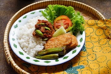 a plate of rice served with sambal and vegetables  