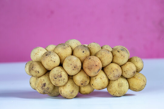 Longkong on a white table with a pink back.