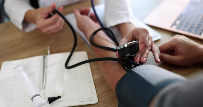 Cardiologist therapist performing blood pressure check procedure with tonometer and stethoscope