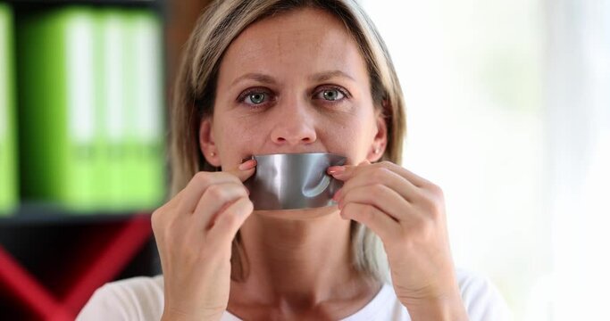 Protesting woman sticks tape on mouth and is silent