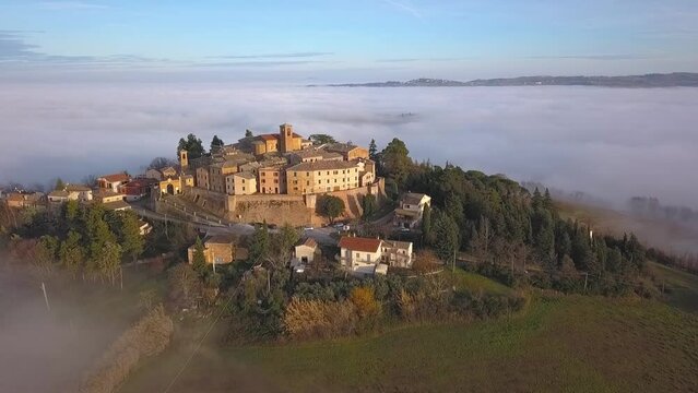 Aerial slow movement around medieval village of Arcevia surrounded by buildings