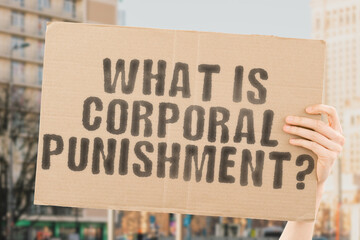 The question " What is corporal punishment? " is on a banner in men's hands with blurred background. Education. Teacher. Teenager. Boy. Person. Man. Afraid. Anger. Fear. Hitting. Sad. Obedience