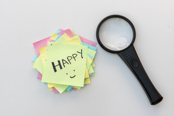 The word happy hand written on a yellow sticky note. Searching for a happy life concept