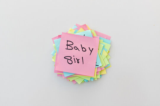 Baby girl gender reveal handwritten on a pink sticky note with white isolated background