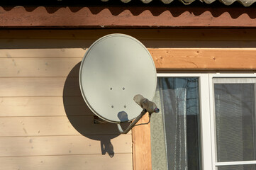 A satellite dish is hanging on the wall of a wooden house