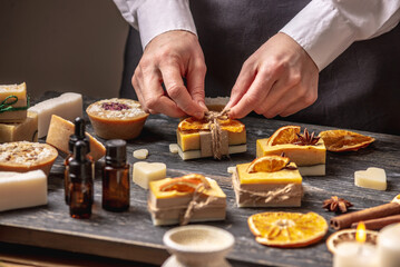 Woman is packing a beautiful natural soap decorated with a slice of orange and a star anise....