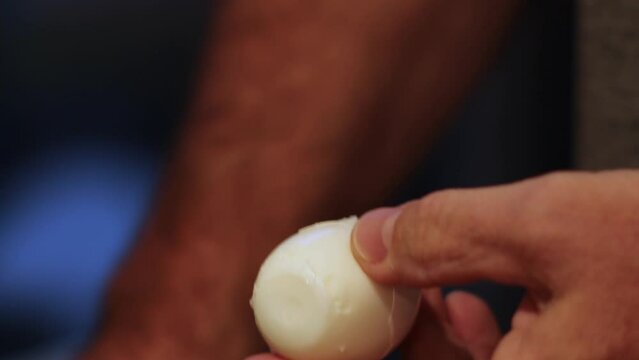 Close-up of man's hands peeling hard boiled egg with Bokeh background