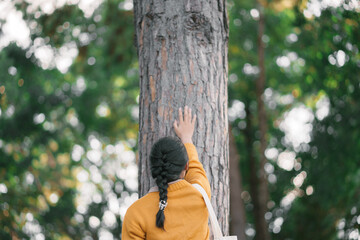 New generation young woman and the big tree in the forest. The environment is of connection sustainable development. renewable energy is environmentally friendly. Technology and new forward.