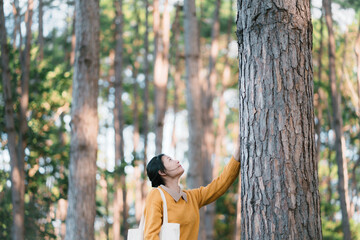 New generation young woman and the big tree in the forest. The environment is of connection sustainable development. renewable energy is environmentally friendly. Technology and new forward.