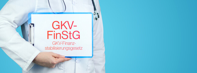 GKV-FinStG (GKV-Finanzstabilisierungsgesetz). Arzt mit Stethoskop hält blaues Klemmbrett. Text...
