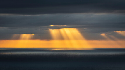 Fototapeta na wymiar Light rays shining through clouds over the ocean