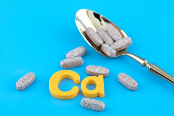 Fototapeta na wymiar Calcium tablets and symbol Ca on blue background