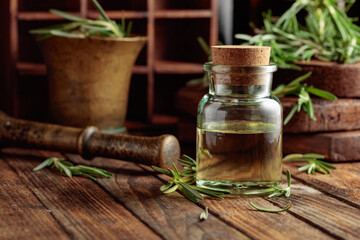 Rosemary essential oil or infusion on an old wooden table.