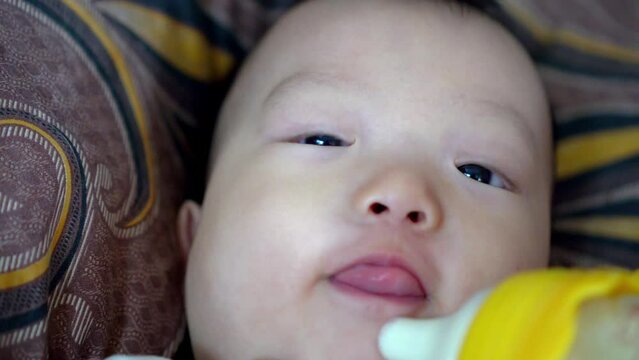 Close up baby face while holding bottle drinking milk