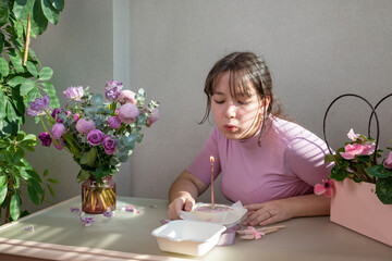 Portrait of a joyful girl making a wish while holding a birthday cake and blowing out a candle