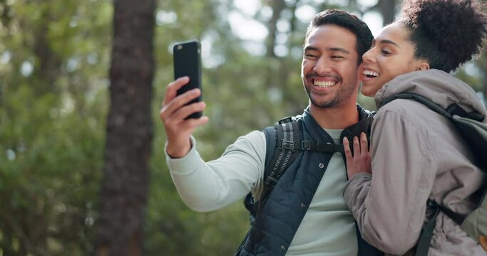 Hiking, selfie and young couple in forest smiling, happy and enjoy nature together. Fitness, wellness and Asian man with black woman taking picture with phone on adventure, trekking and walk in woods
