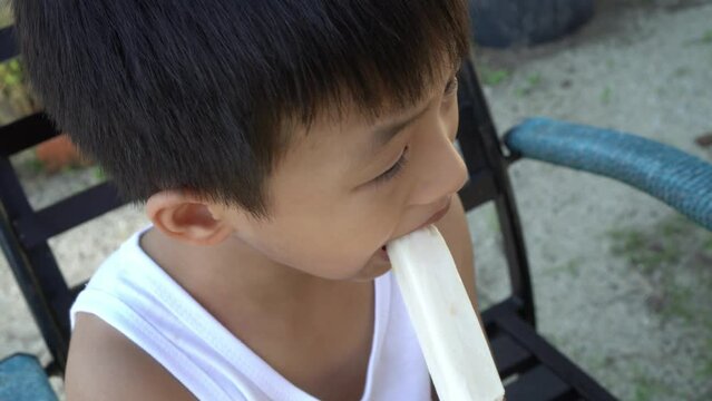 Chinese kid eat ice cream stick at outdoor