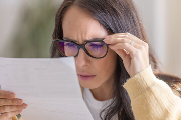 The woman has vision problems and reads the letter very close to her eyes and glasses