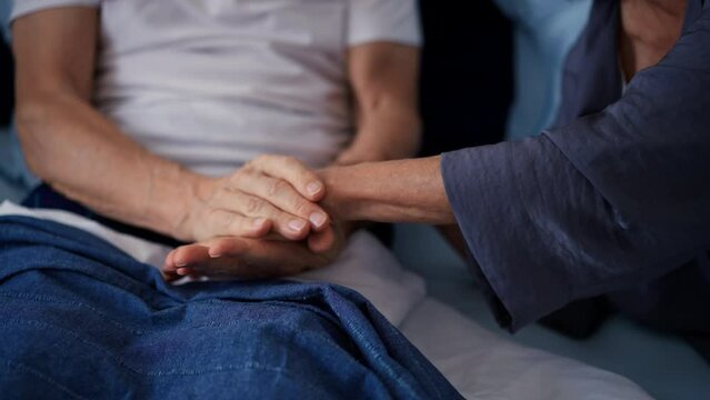 Senior couple in bed touching hands.